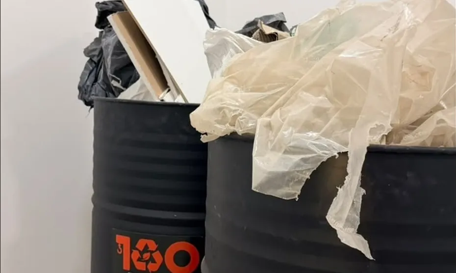 Dois coletores cheios de papelão e plástico num apartamento
