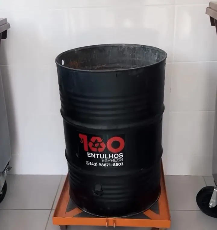 Coletor preto de 200 litros com o adesivo da 100 Entulhos, sobre a base laranja com rodinhas